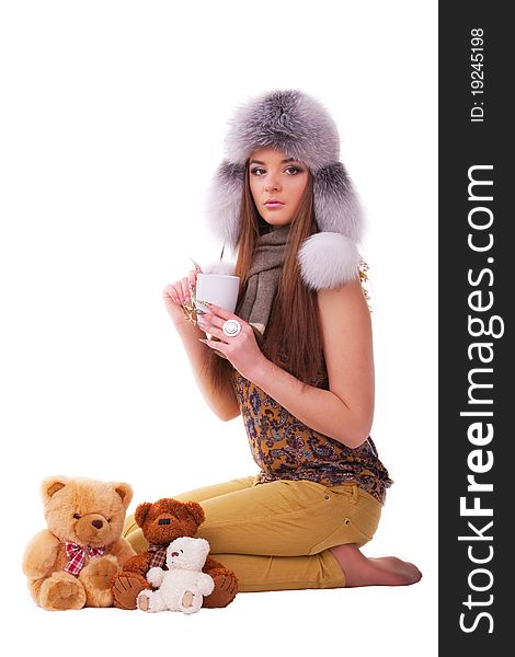 Beautiful brunette in a fur hat sitting next to a few teddy bears