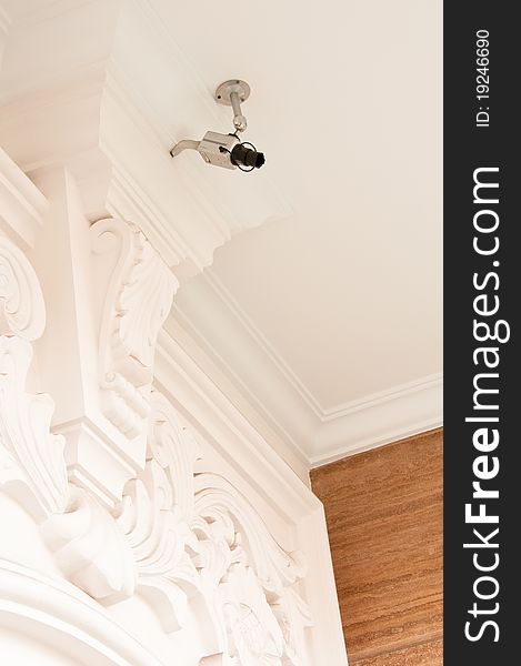 A security surveillance camera installed on a carved ceiling