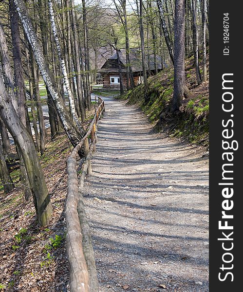 A path or unpaved road through the early spring forest in a countryside, cottage in the background; Roznov pod Radhostem, Czech Republic. A path or unpaved road through the early spring forest in a countryside, cottage in the background; Roznov pod Radhostem, Czech Republic.