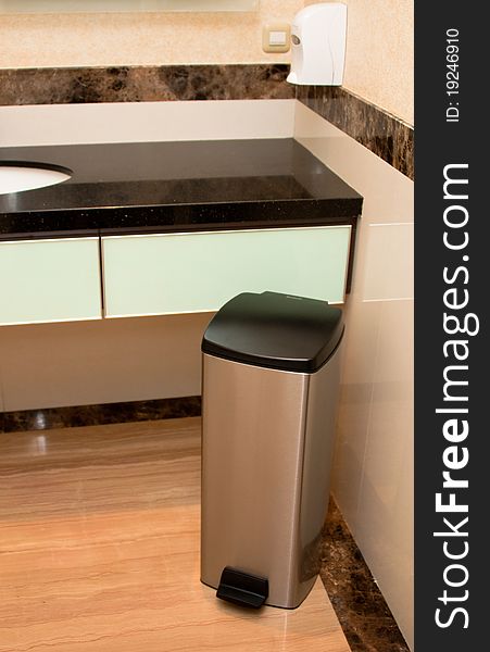 A stainless steel bin inside the luxurious marble washroom. A stainless steel bin inside the luxurious marble washroom