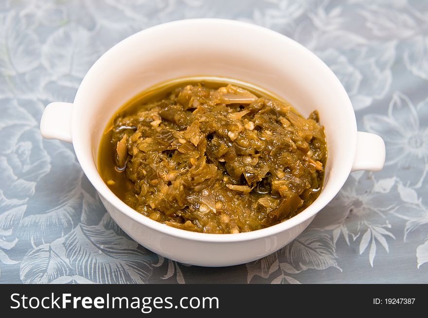 A pounded spicy green chili paste on a white bowl. A pounded spicy green chili paste on a white bowl