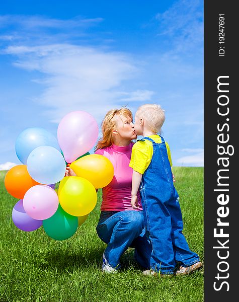 Happy mother and son with balloons outdoor on a summer day