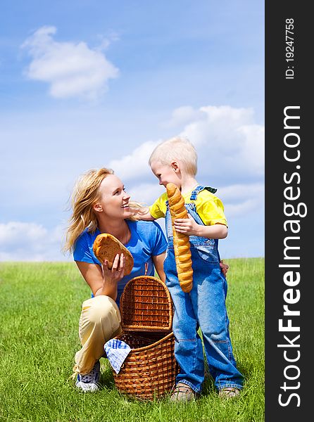Happy young  woman and her son having a picnic outdoor on a summer day (focus on the woman). Happy young  woman and her son having a picnic outdoor on a summer day (focus on the woman)