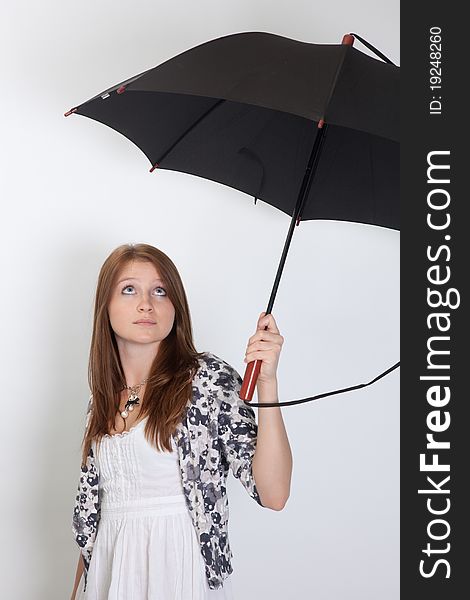 The girl holds the big umbrella and looks upwards. The girl holds the big umbrella and looks upwards