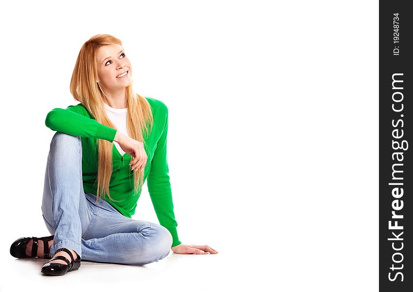 Beautiful  young  woman sitting on the floor against white background and looking to the right, copy space for your text. Beautiful  young  woman sitting on the floor against white background and looking to the right, copy space for your text