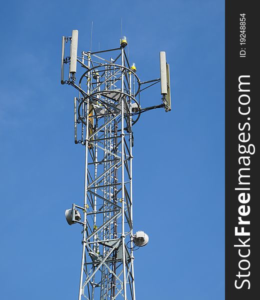 Telecommunication tower with different antenna under blue sky.