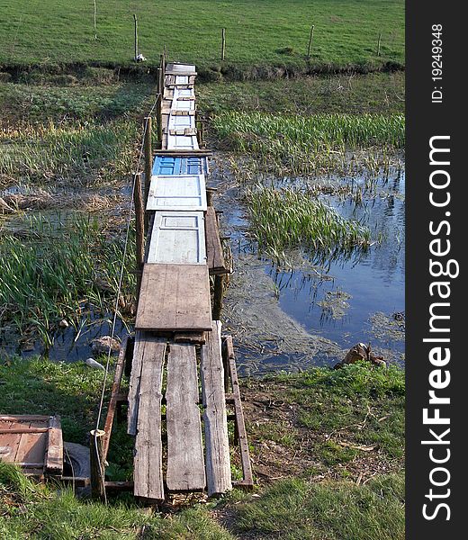 A footbridge over a rural pond. A footbridge over a rural pond.