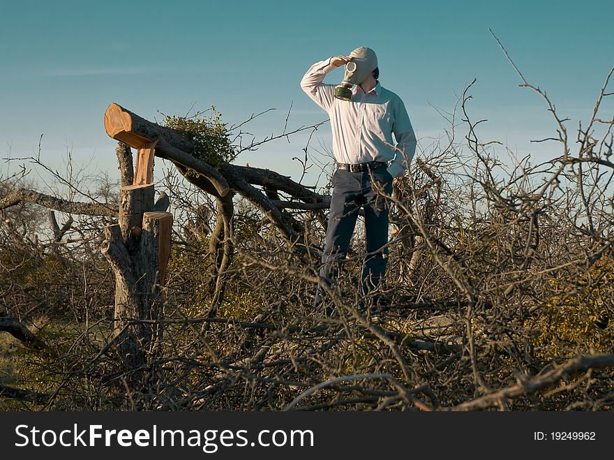 A Man in the Gas Mask surrounded by broken trees.