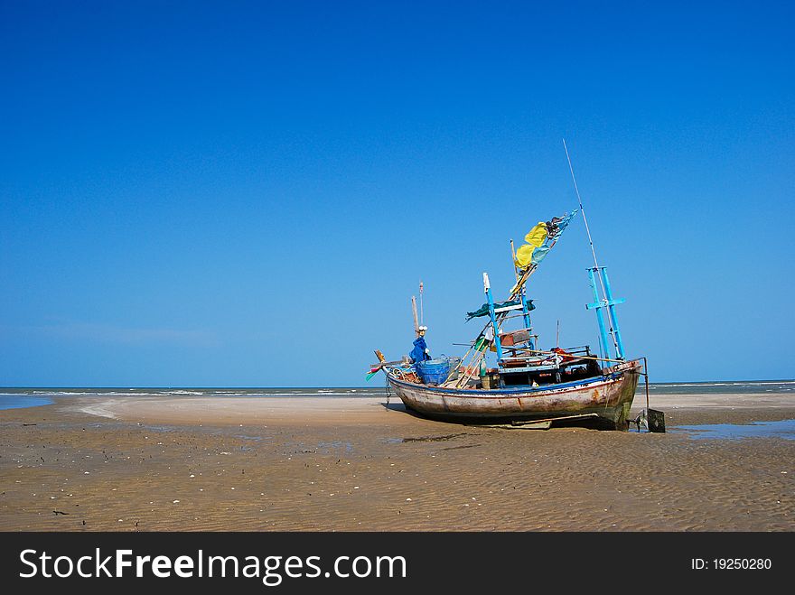 Fisherman boat on the sea shore , with bright blue sky background