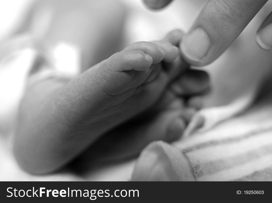 A soft focus photo of a person touching baby toes. A soft focus photo of a person touching baby toes