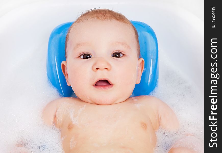 Cute six months old baby taking a relaxing bath with foam. Cute six months old baby taking a relaxing bath with foam
