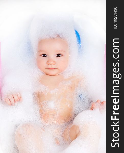 Cute six months old baby taking a relaxing bath with foam. Cute six months old baby taking a relaxing bath with foam