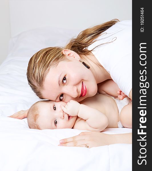 Young mother and her six months old baby on the bed at home. Young mother and her six months old baby on the bed at home