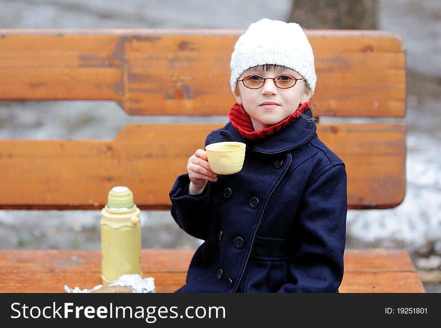 Little girl eats her lunch in the spring park