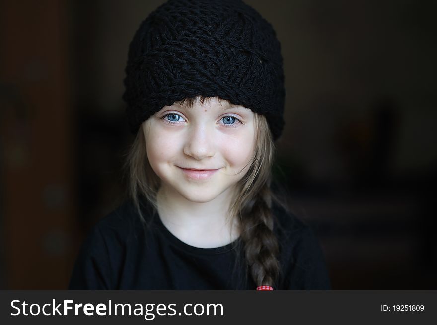 Portrait of cute little girl in black hat on dark background