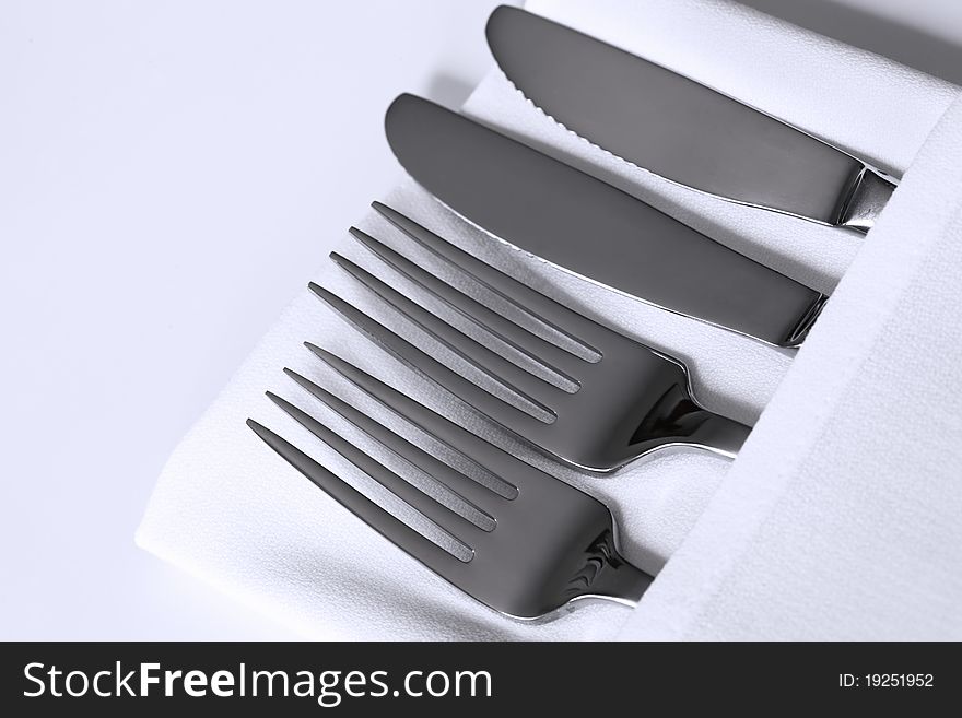 Knives and forks with white linen napkin. Knives and forks with white linen napkin.