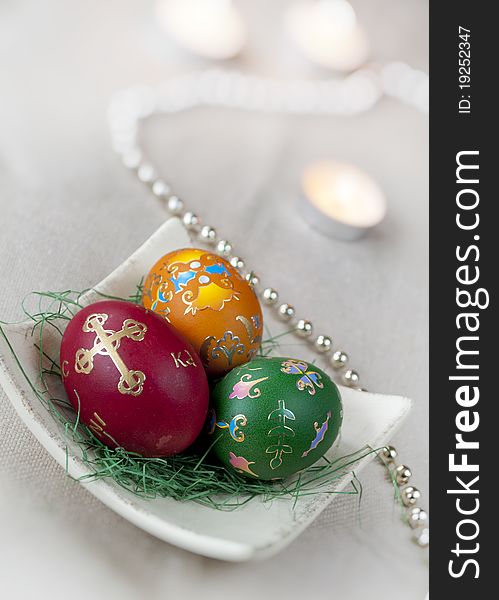 Three colored Easter eggs with decoration and candles