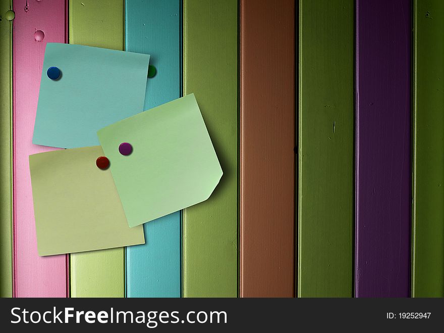 Memo notes over a colorful wooden wall fitted with thumbtack. Memo notes over a colorful wooden wall fitted with thumbtack