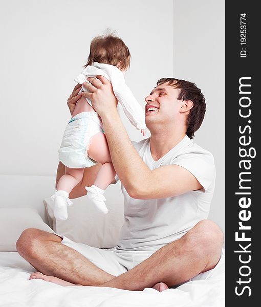 Young father with his six months old daughter on the bed at home. Young father with his six months old daughter on the bed at home