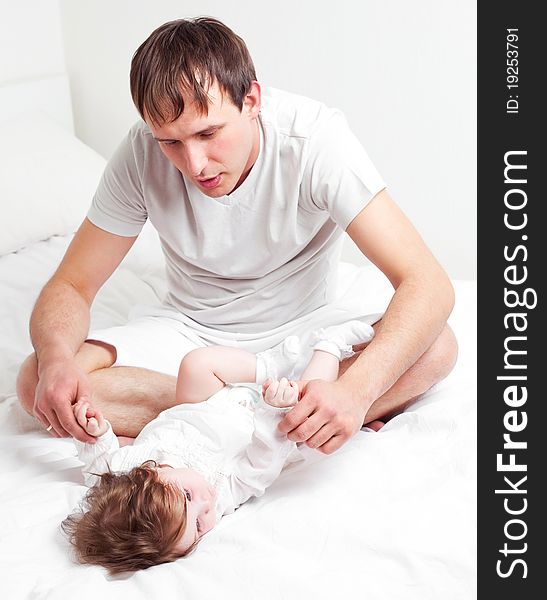 Young father with his six months old daughter on the bed at home. Young father with his six months old daughter on the bed at home