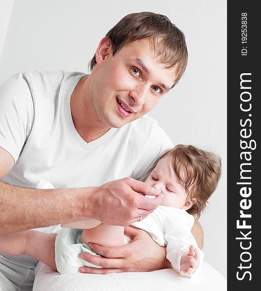 Young father feeding his his six months old daughter on the bed at home. Young father feeding his his six months old daughter on the bed at home