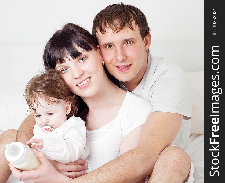 Happy family, mother ,father and their baby on the bed at home