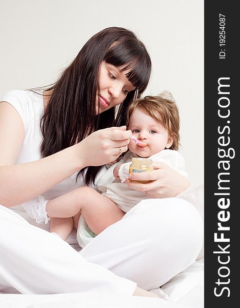 Happy young mother feeding her baby with yogurt (focus on the baby). Happy young mother feeding her baby with yogurt (focus on the baby)