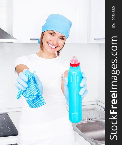 Beautiful happy young housewife wearing gloves and holding a detergent