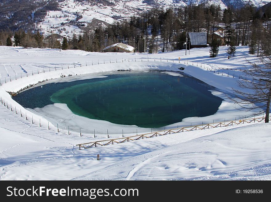 Beautiful artificial lake in the mountain in winter near village. Beautiful artificial lake in the mountain in winter near village