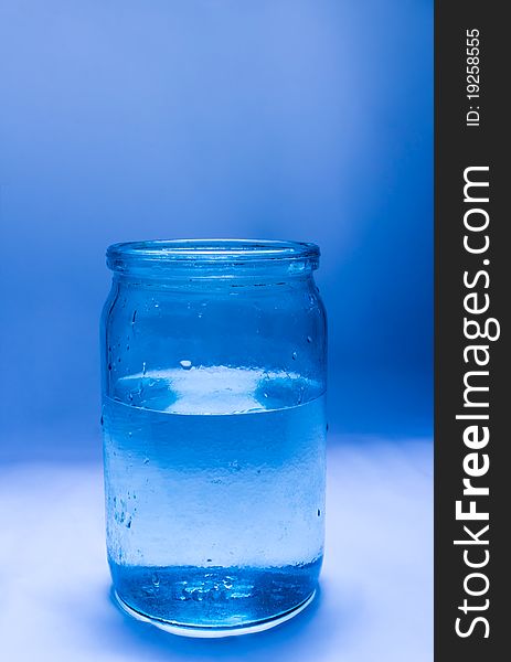 Glass jar filled with water on a blue background. Glass jar filled with water on a blue background