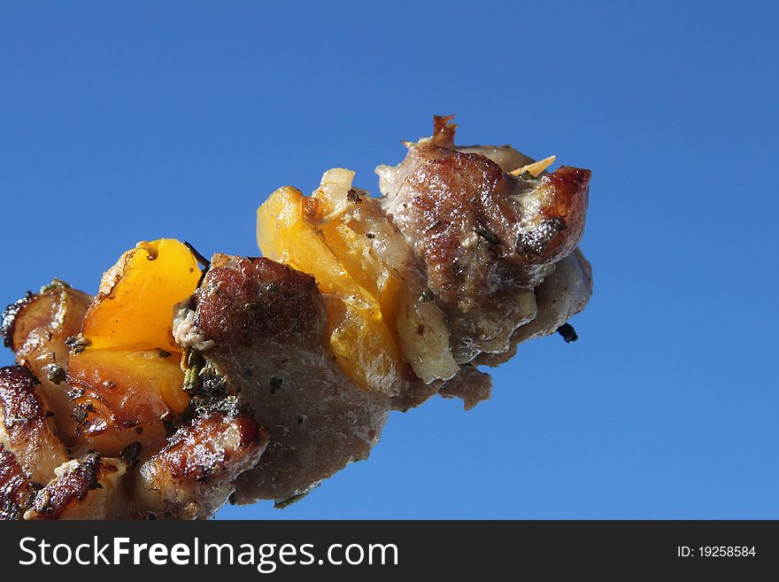 Shish Kebab on the blue sky with yellow pepper and spices