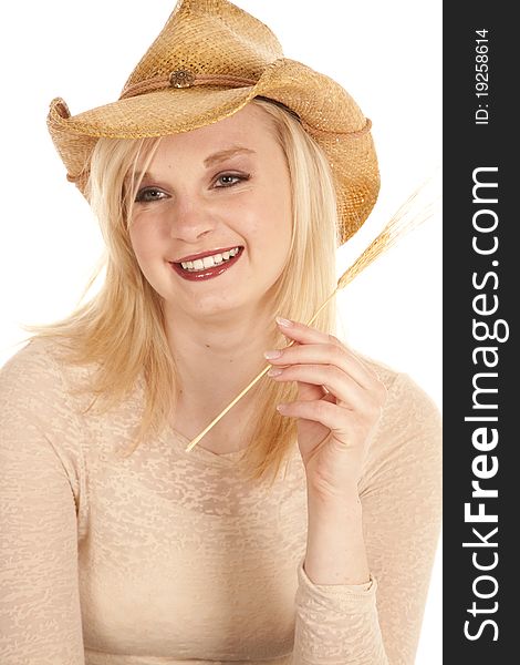 A cowgirl laughing while she holds onto a piece of wheat. A cowgirl laughing while she holds onto a piece of wheat.