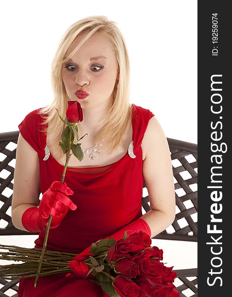 A beautiful teen sitting in her red dress on a metal bench, looking cross eyed at a single rose. A beautiful teen sitting in her red dress on a metal bench, looking cross eyed at a single rose.