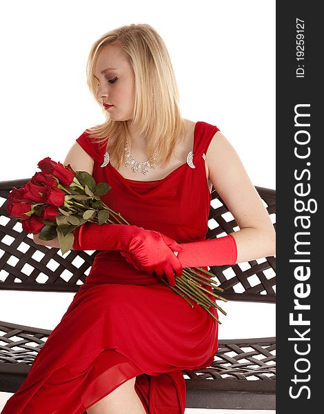 A beautiful teen sitting in her red dress on a metal bench looking down at her roses. A beautiful teen sitting in her red dress on a metal bench looking down at her roses.