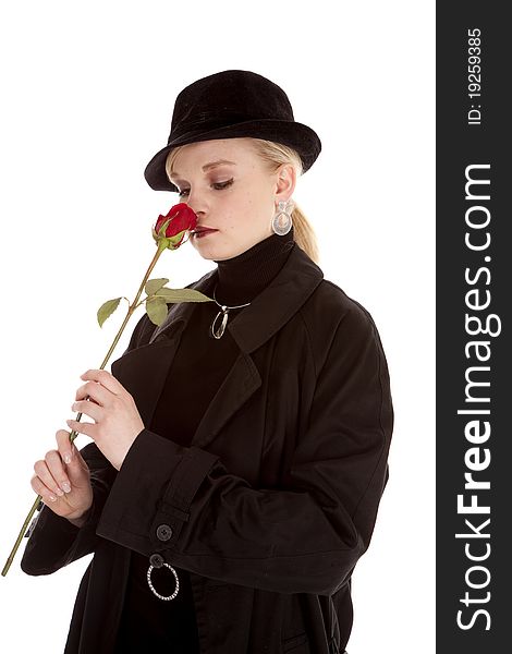A beautiful girl in a black hat and coat smelling a red rose. A beautiful girl in a black hat and coat smelling a red rose.
