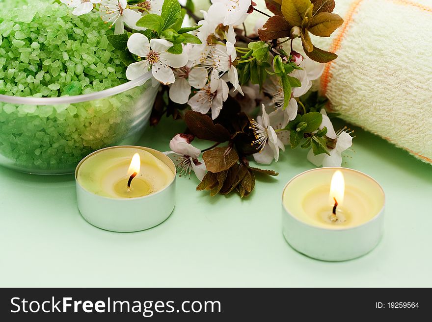 Green sea salt and a lit candle on a green background. Green sea salt and a lit candle on a green background