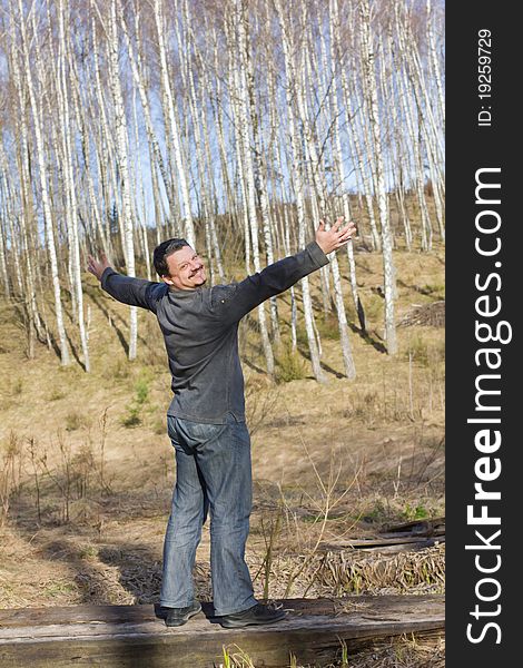 Man stands arms outstretched as if embracing the birch grove. Man stands arms outstretched as if embracing the birch grove