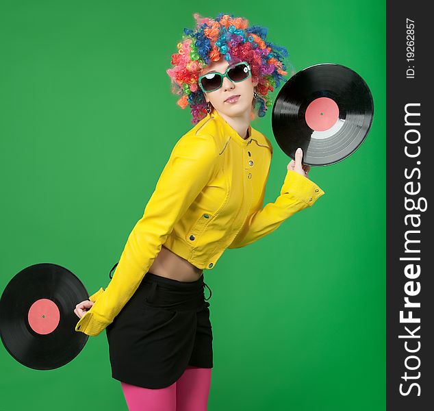 The girl in a color wig with a disk on green background. The girl in a color wig with a disk on green background