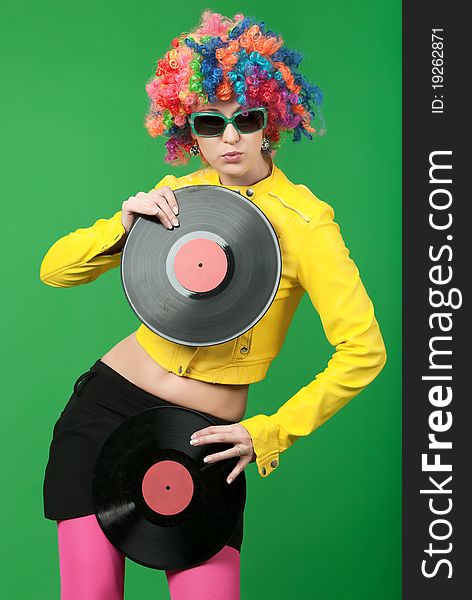 The girl in a color wig with a disk on green background. The girl in a color wig with a disk on green background