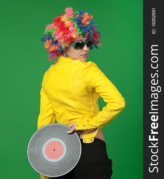 The girl in a color wig with a disk on green background. The girl in a color wig with a disk on green background