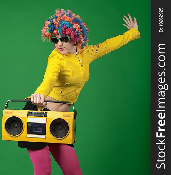 The girl in a color wig with the old tape recorder on green background. The girl in a color wig with the old tape recorder on green background