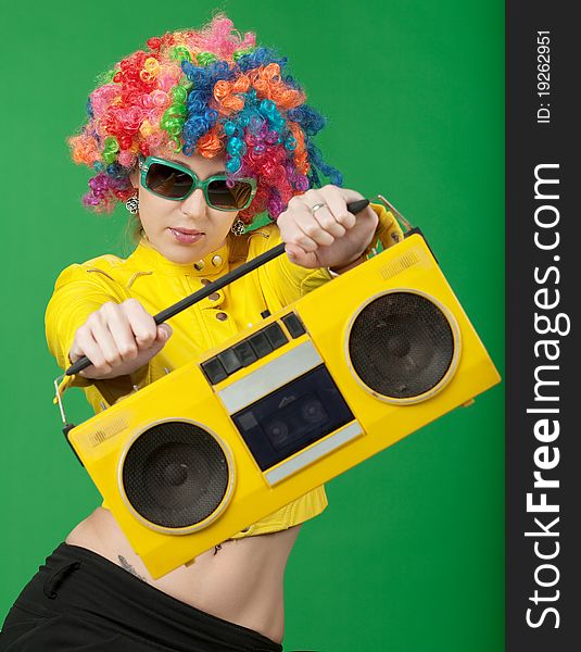The girl in a color wig with the old tape recorder on green background. The girl in a color wig with the old tape recorder on green background