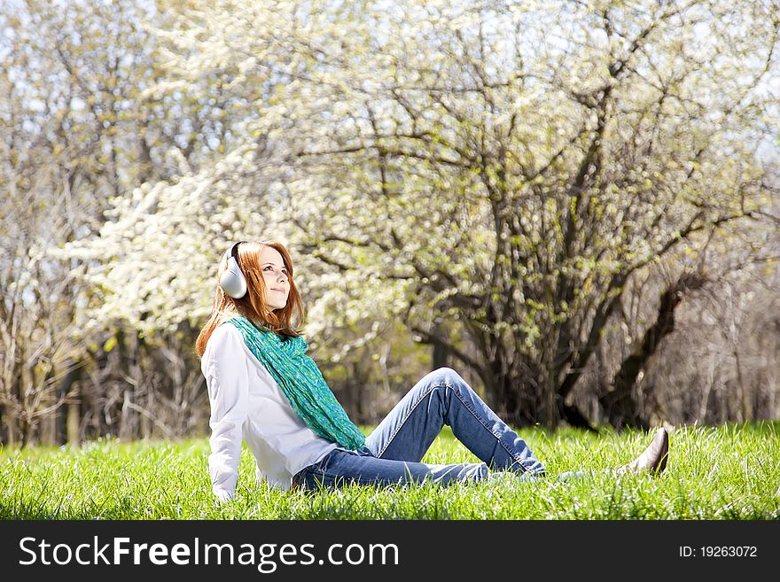 Redhead girl with headphone in the park.