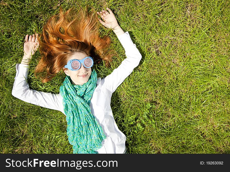 Girl lies at green grass in the park.