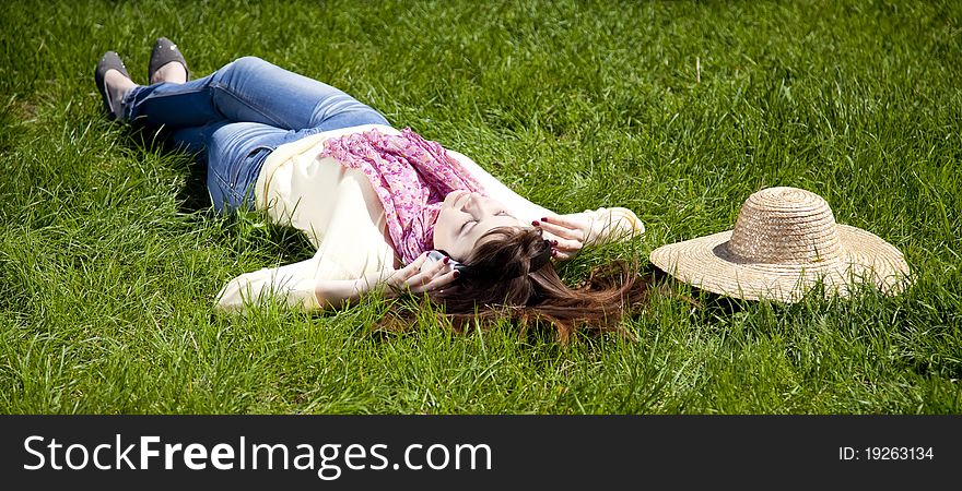 Brunette Girl With Headphone Lies In The Park