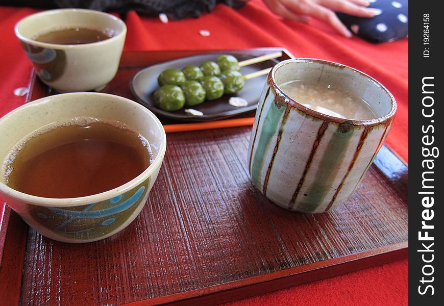 Closeup view of some delicious traditional Japanese desserts of tea dango, sweet rice wine and tea.