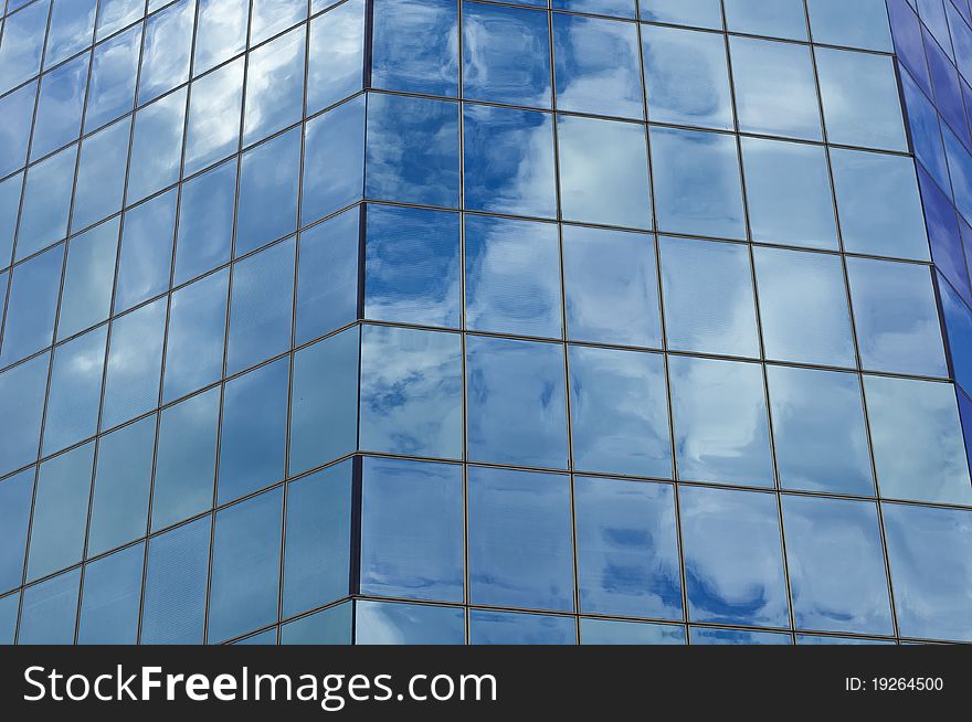 Sky and clouds reflecting in a glass facade of a business building. Sky and clouds reflecting in a glass facade of a business building.