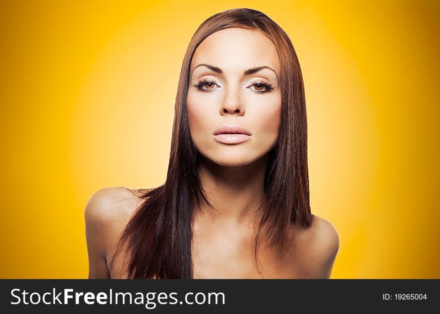 Portrait of beautiful brunette woman on yellow background