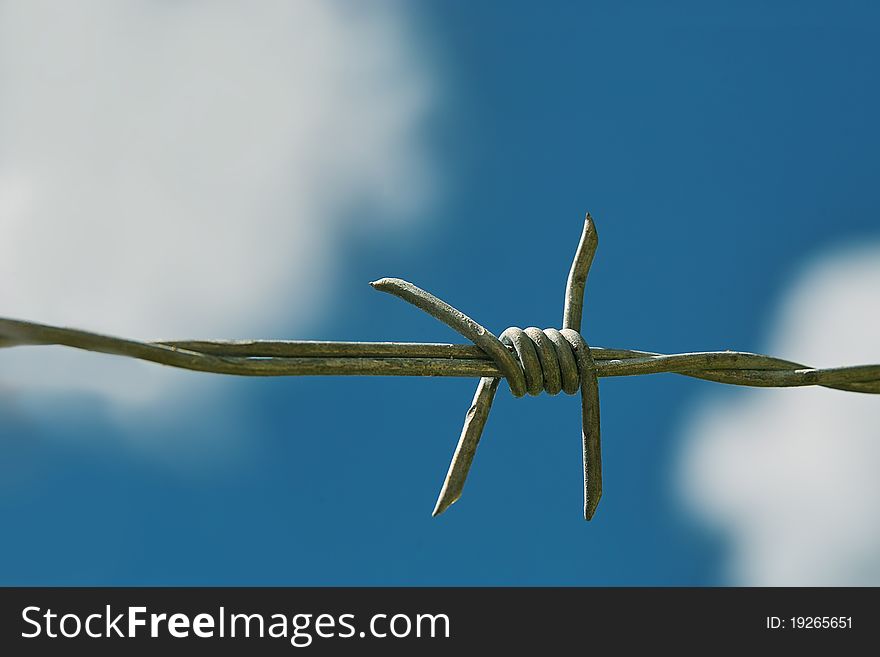 Barbed wire is on the beautiful blue sky, white clouds background. Barbed wire is on the beautiful blue sky, white clouds background.