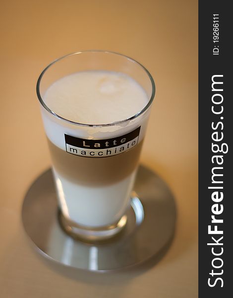 Latte macchiato on saucer on a table